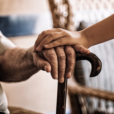 Two hands clasped over a walking stick